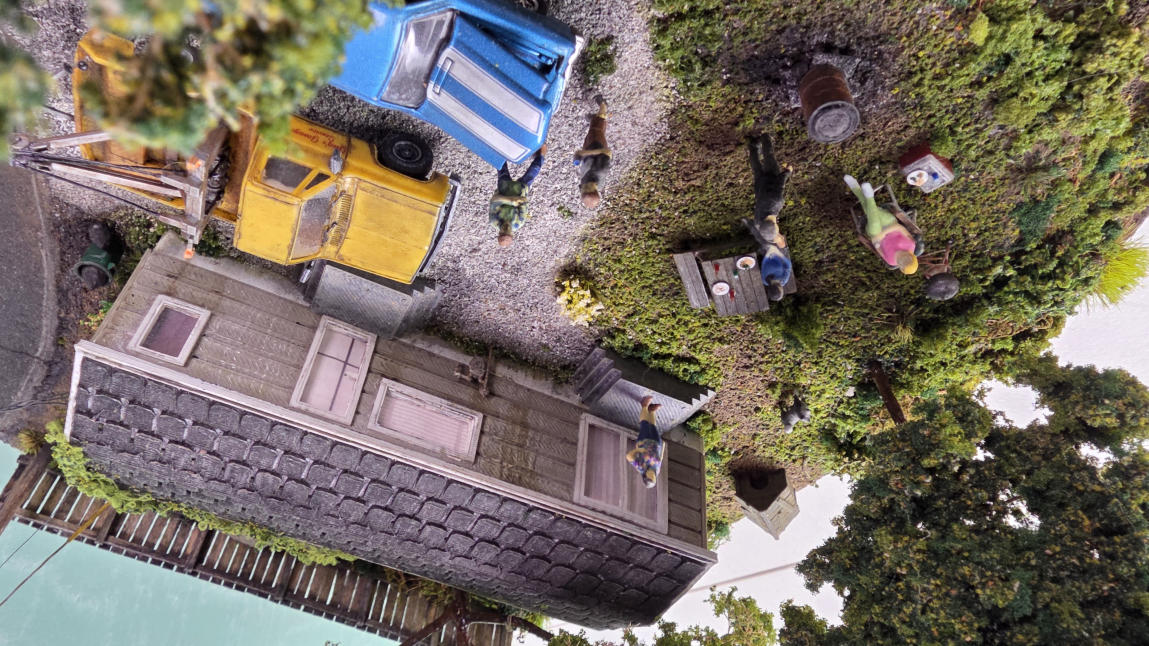 Overhead view of the twelve-inch diorama — gravel drive, trailer, picnic table, burn barrel, and dog with doghouse